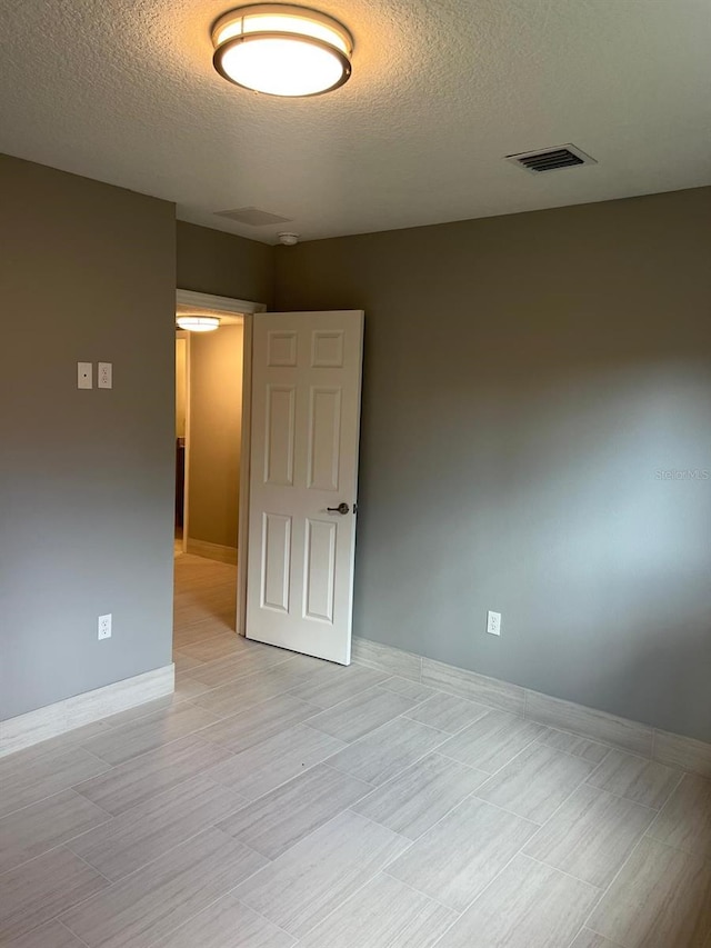 unfurnished room featuring a textured ceiling