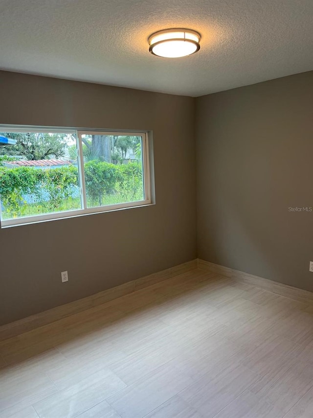 empty room with a textured ceiling and light hardwood / wood-style floors