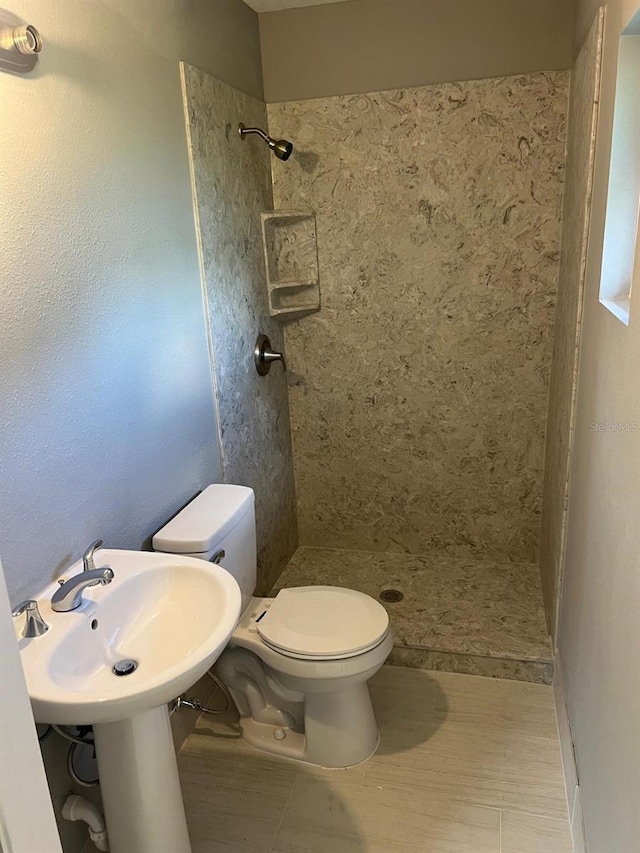 bathroom featuring tiled shower and toilet