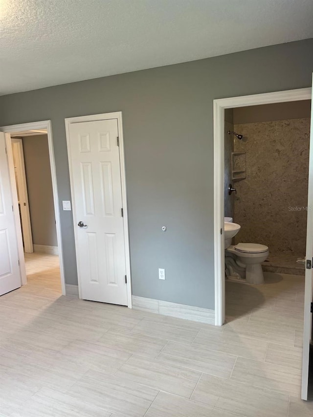 unfurnished bedroom with ensuite bathroom and a textured ceiling