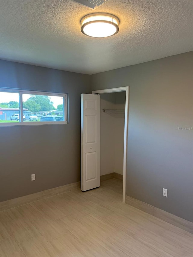 unfurnished bedroom featuring a closet, light hardwood / wood-style floors, and a textured ceiling