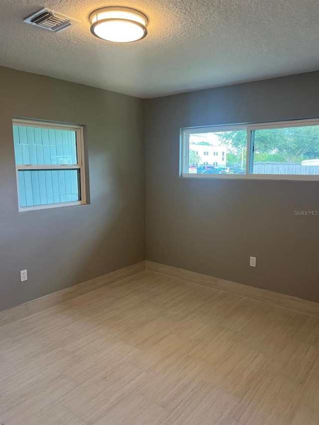 spare room featuring a textured ceiling and light hardwood / wood-style flooring