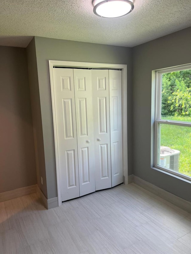 unfurnished bedroom with a closet, light hardwood / wood-style floors, and a textured ceiling