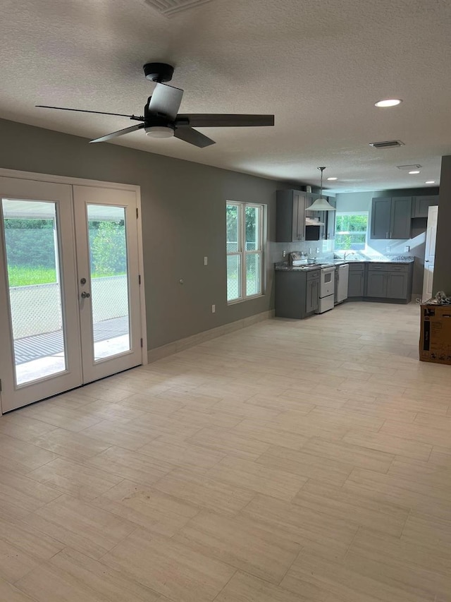 unfurnished living room with french doors, ceiling fan, and a healthy amount of sunlight