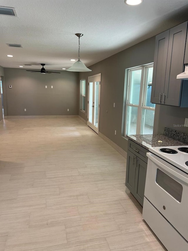 kitchen featuring ceiling fan, pendant lighting, exhaust hood, electric range, and light stone countertops