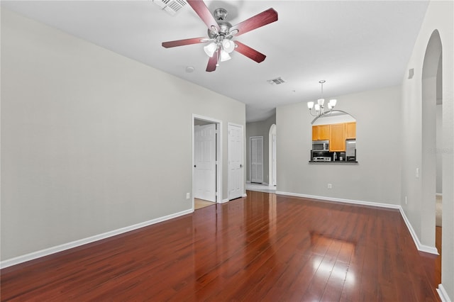 empty room with ceiling fan with notable chandelier and dark hardwood / wood-style flooring