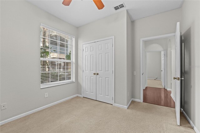 unfurnished bedroom featuring ceiling fan, light carpet, and a closet