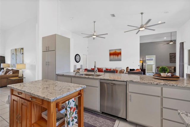 kitchen featuring light stone counters, white cabinets, light tile patterned flooring, dishwasher, and a high ceiling