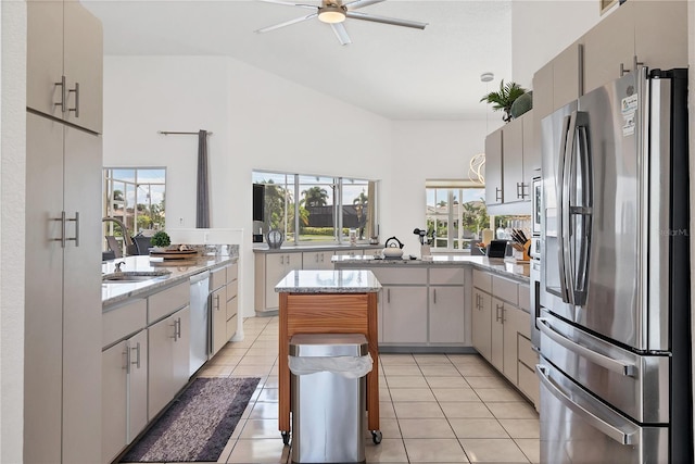 kitchen featuring light tile patterned flooring, sink, kitchen peninsula, a kitchen island, and stainless steel appliances