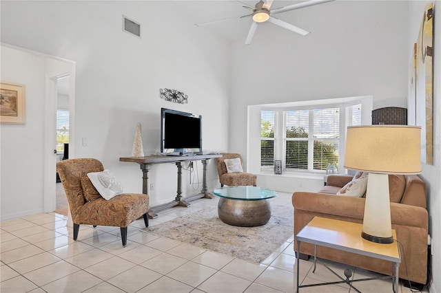 living room with ceiling fan, a towering ceiling, and light tile patterned floors