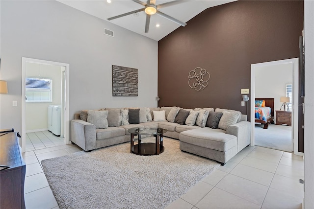 tiled living room with ceiling fan and high vaulted ceiling