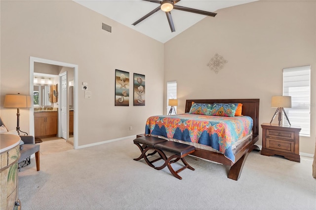 bedroom featuring ceiling fan, light colored carpet, sink, ensuite bath, and high vaulted ceiling