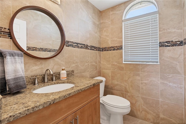 bathroom with toilet, tile walls, and vanity