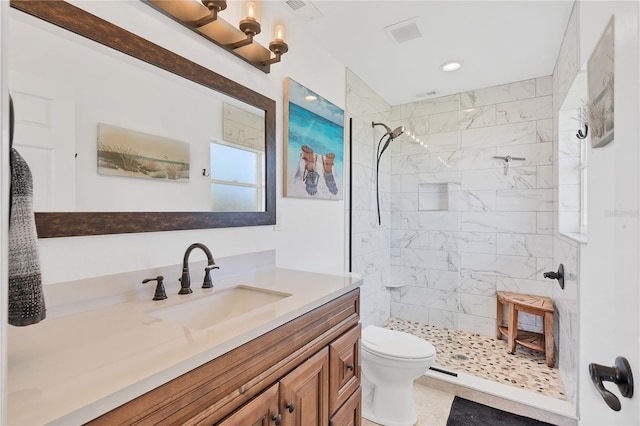 bathroom featuring a tile shower, toilet, and vanity