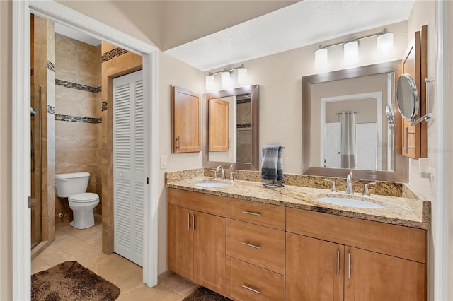 bathroom with tiled shower, toilet, tile patterned flooring, and vanity