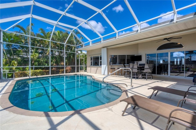 view of swimming pool featuring glass enclosure, ceiling fan, and a patio area