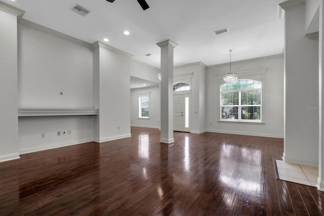 unfurnished living room featuring a wealth of natural light, crown molding, ceiling fan with notable chandelier, and dark hardwood / wood-style floors