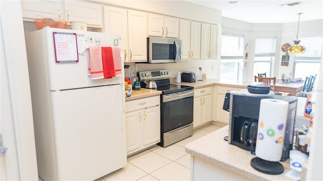 kitchen with appliances with stainless steel finishes, hanging light fixtures, and light tile patterned floors