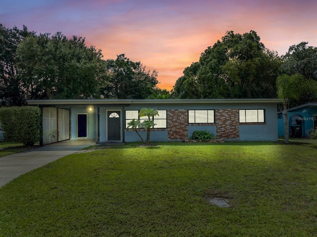 ranch-style home with a lawn and a carport