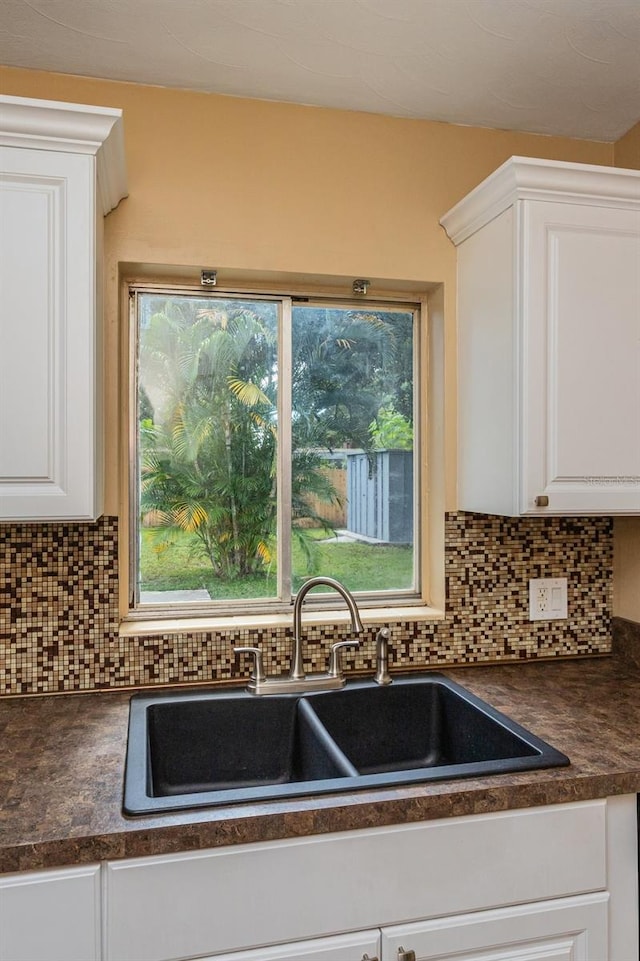 kitchen featuring sink, white cabinetry, and backsplash