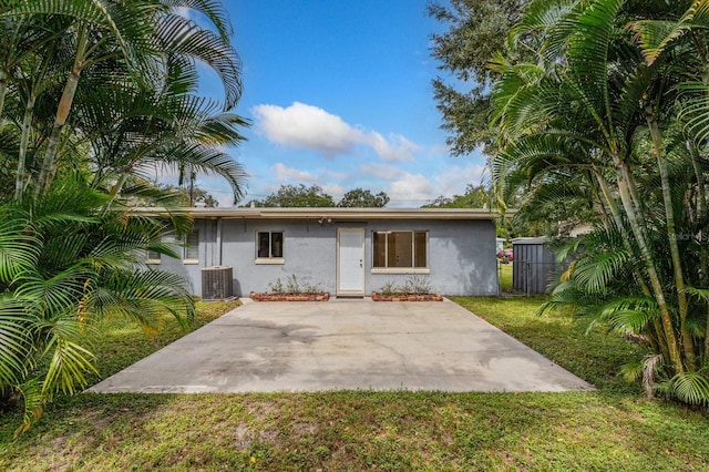 view of front of property featuring a front lawn, a patio area, and central air condition unit