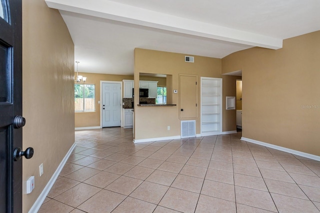 unfurnished living room with a chandelier, beam ceiling, and light tile patterned floors