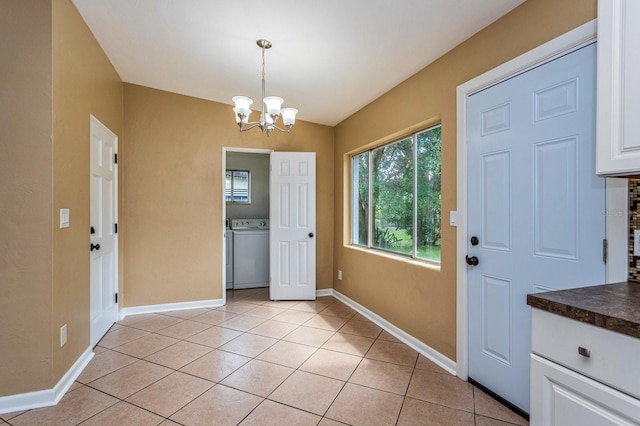 doorway featuring a chandelier, washer / clothes dryer, lofted ceiling, and light tile patterned flooring