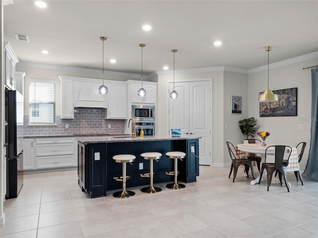 kitchen with white cabinetry, appliances with stainless steel finishes, an island with sink, and hanging light fixtures