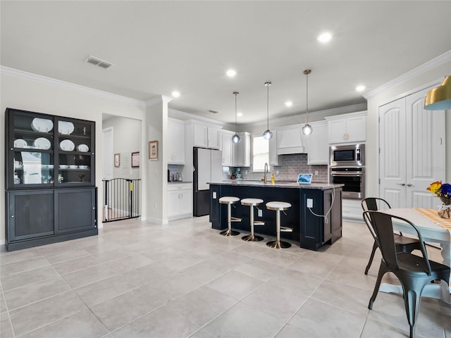 kitchen with white cabinets, a kitchen island, a breakfast bar, decorative light fixtures, and stainless steel appliances