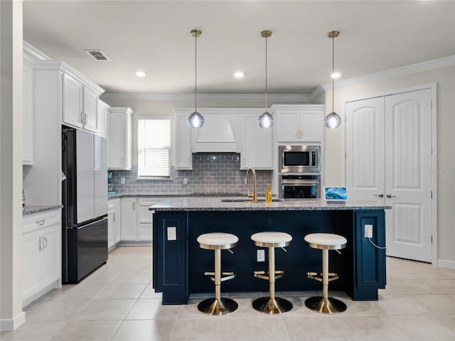 kitchen featuring white cabinets, stainless steel appliances, sink, and an island with sink