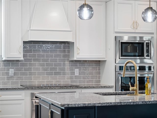 kitchen with appliances with stainless steel finishes, custom range hood, white cabinetry, and backsplash