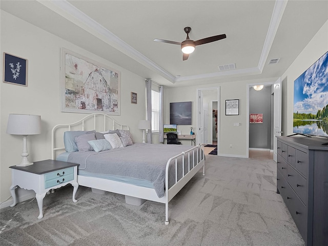 bedroom featuring crown molding, light carpet, a tray ceiling, and ceiling fan