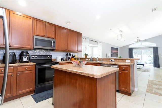 kitchen with stainless steel appliances, vaulted ceiling, a center island, and light tile patterned floors