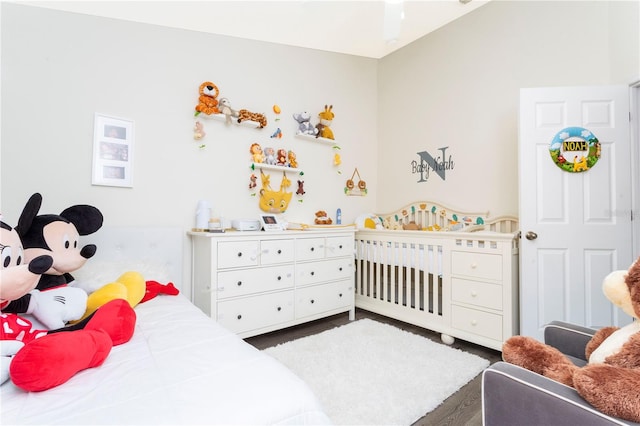 bedroom featuring a nursery area and dark hardwood / wood-style floors