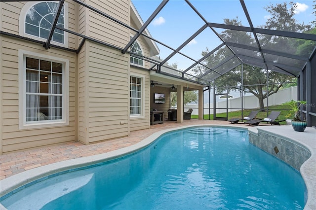 view of swimming pool with ceiling fan, a lanai, and a patio area