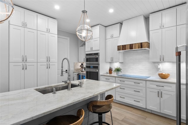 kitchen featuring premium range hood, black electric stovetop, white cabinetry, and sink