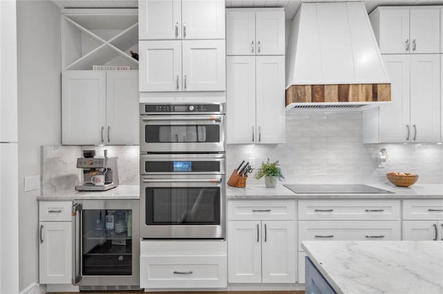 kitchen with premium range hood, wine cooler, white cabinetry, black electric stovetop, and stainless steel double oven