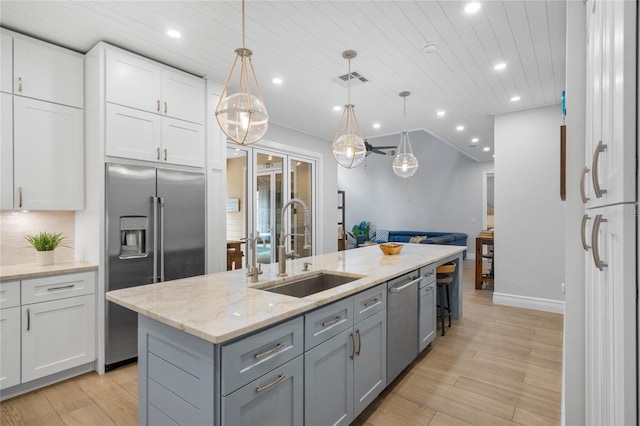 kitchen featuring gray cabinets, sink, a center island with sink, appliances with stainless steel finishes, and decorative light fixtures