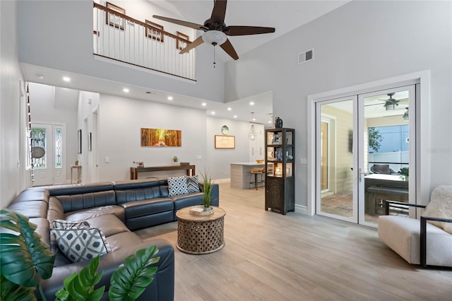 living room with high vaulted ceiling, ceiling fan, and light hardwood / wood-style flooring