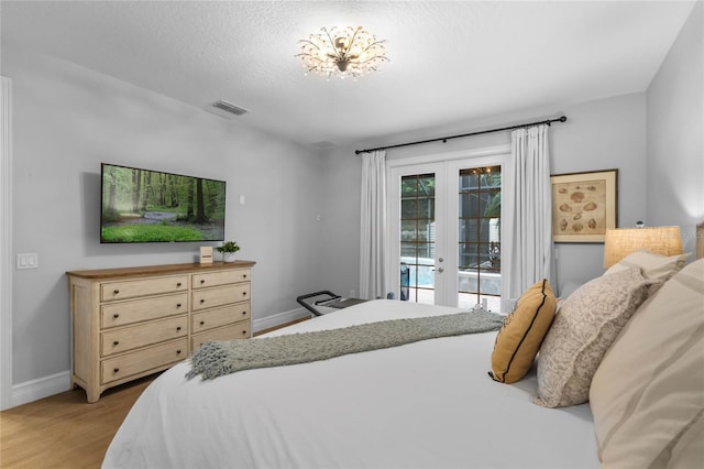 bedroom with french doors, a textured ceiling, light wood-type flooring, and access to outside