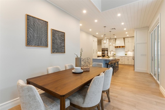 dining space with recessed lighting, light wood-style flooring, and baseboards