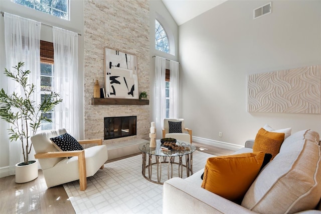 living room with high vaulted ceiling, visible vents, a fireplace, and baseboards