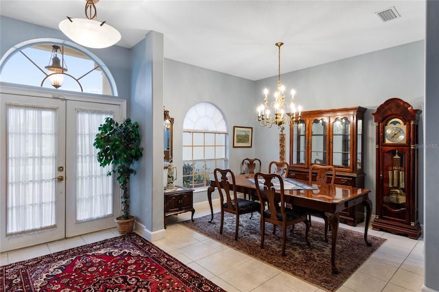 tiled dining space featuring a notable chandelier and french doors