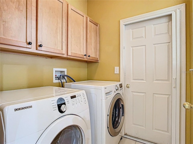 laundry area featuring washing machine and dryer, light tile patterned flooring, and cabinets