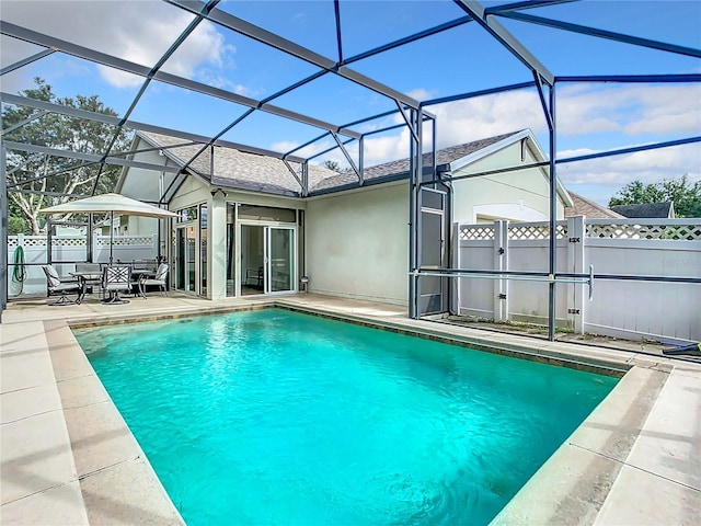 view of pool with glass enclosure and a patio area