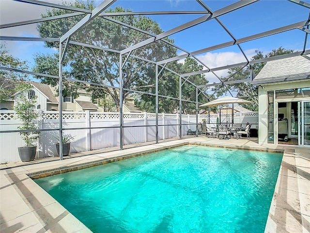 view of pool with glass enclosure and a patio area