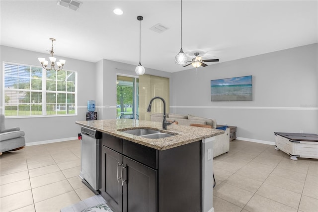 kitchen with light stone countertops, decorative light fixtures, stainless steel dishwasher, a kitchen island with sink, and sink