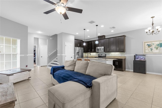 living room with ceiling fan with notable chandelier, sink, and light tile patterned floors