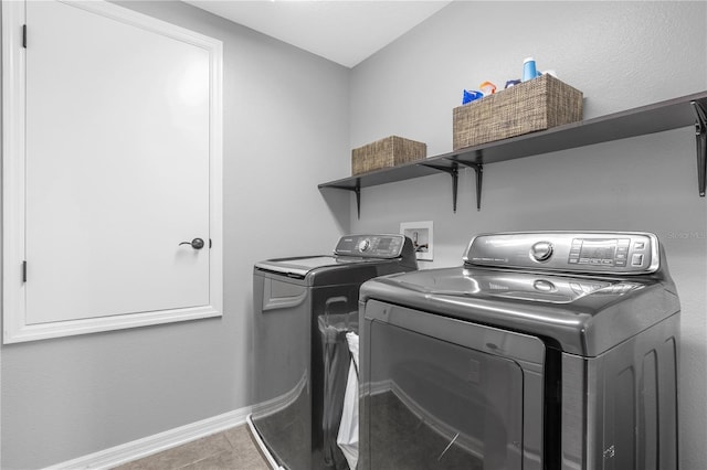 clothes washing area featuring tile patterned flooring and washing machine and clothes dryer