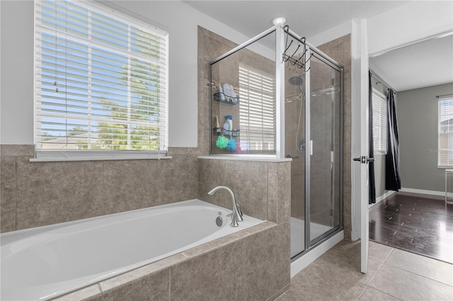 bathroom featuring plus walk in shower, tile patterned flooring, and a healthy amount of sunlight